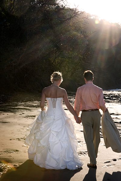Bride and groom holding hands on beach