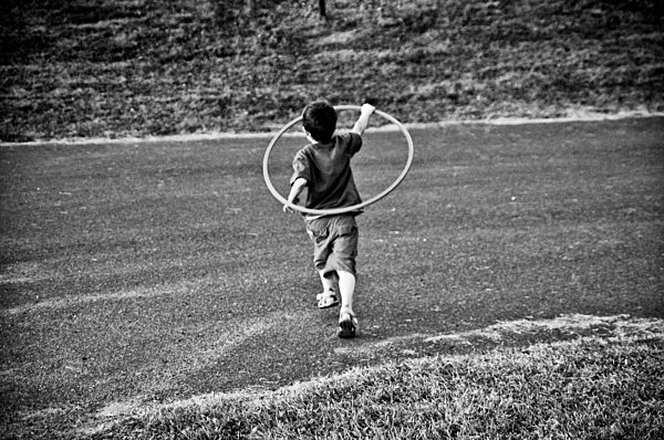 Young boy running with hula hoop, Otterburn Park, Quebec