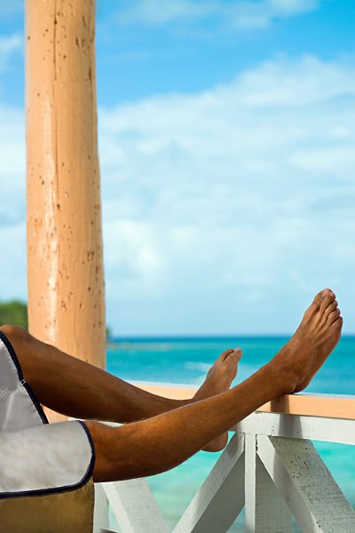 Man on vacation with legs resting on veranda rail