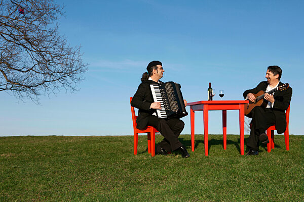 Two men playing accordion and guitar outdoors