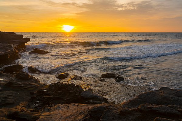 Golden Sunset Over The Ocean With A View Of The Coastline; Bali Island, Indonesia