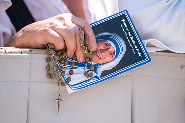 A woman holds a picture of Mother Teresa and a Rosary.