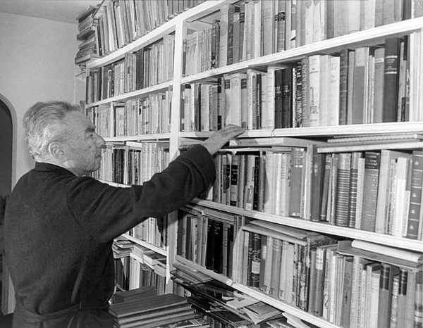 Erich Kästner in front of his book shelve