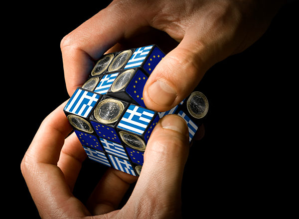 Hands are holding a Rubik's cube with the image motives: flag of the EU, euro coin, and flag of Greece.