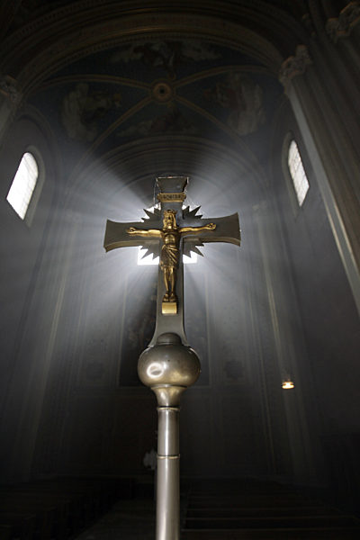 Kreuz vor erleuchtetem Kirchenfenster