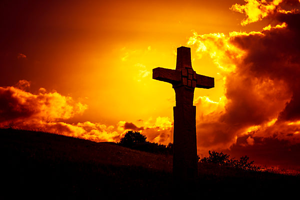 An image of a stone cross in front of a dramatic evening sky