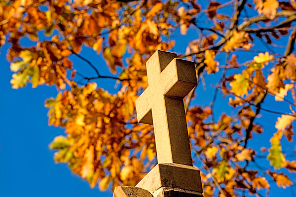 Kreuz an einem Pilgerweg mit herbstlich verfärbtem Laub