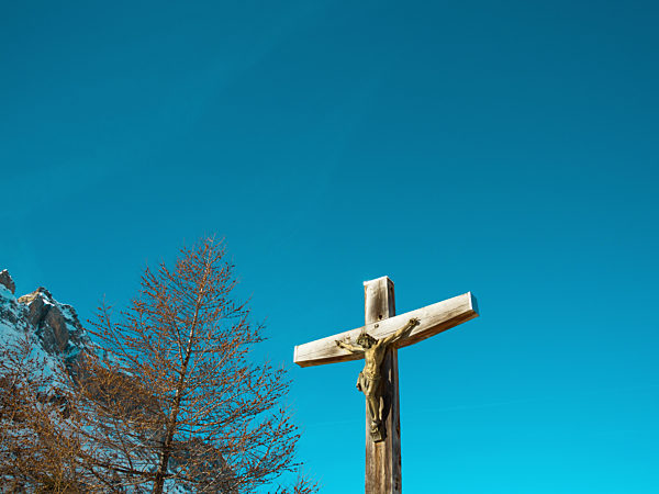 Kruzifix , Christliches Kreuz in den Bergen vor strahlend blauem Himmel