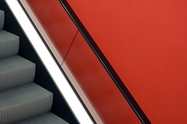 Escalator in front of red wall