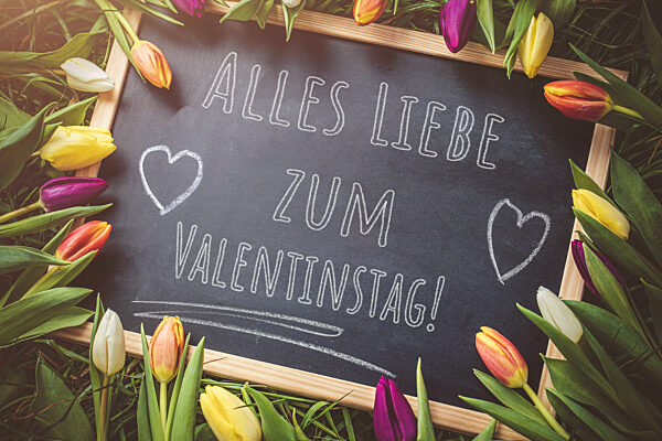 Bavaria, Germany - 11 February 2023: Happy Valentine's Day Greeting On A Chalkboard Decorated With Colorful Tulips Flowers PHOTOMONTAGE