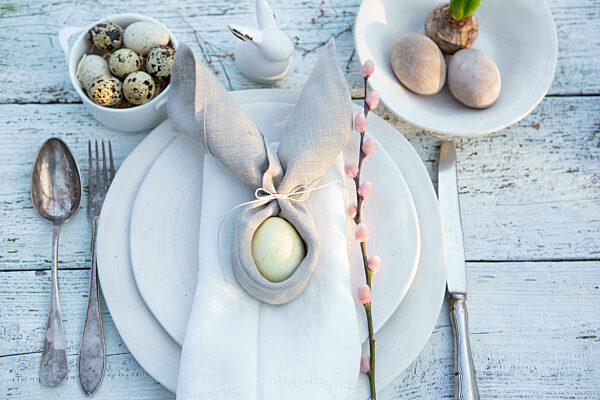 Luxus Oster Dekoration auf einem Tisch in einem Restaurant, Ei Auf einem Teller mit hochwertigem Besteck und Serviette. Frohe Ostern Feiertage Restaurant Konzept