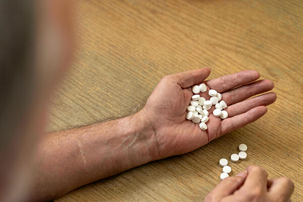 Augsburg, Bavaria, Germany - 27 October 2023: An Old Man Holds A Large Dose Of Medication In His Hand. Tabettes And Medicine Concept