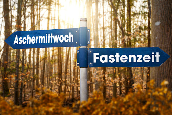 Fastenzeit und Aschermittwoch Schrift auf einem Wegweiser in einem hellen Wald FOTOMONTAGE