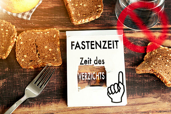 Fastenzeit, Zeit des Verzichts Schriftzug auf einem kaputten Kalenderblatt mit Verbot Symbol über Essen. FOTOMONTAGE
