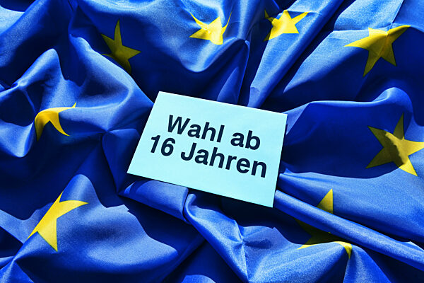Voting Envelope With Inscription From 16 Years Of Age In Front Of EU Flag, Symbolic Photo Of Lowered Voting Age For The 2024 European Elections, Photomontage