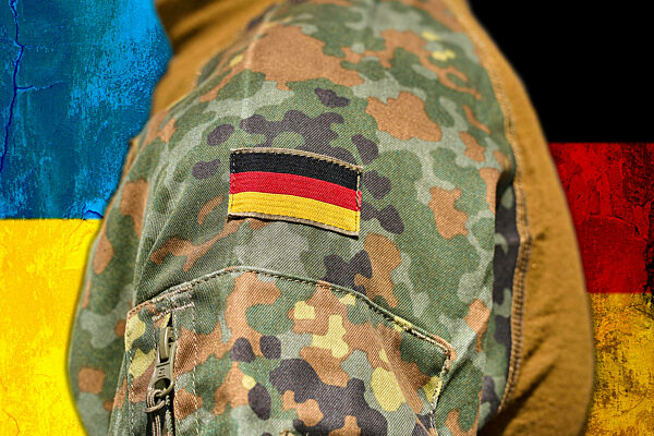August 11, 2024: A Soldier Of The German Armed Forces Stands In Front Of The Ukrainian Flag. Symbolic Image Of Germany's Support In The War Between Russia And Ukraine. PHOTOMONTAGE