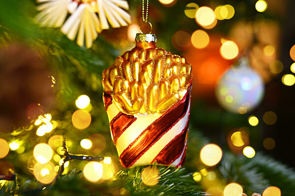 Weihnachtsschmuck in Form einer Tüte Pommes hängt an einem Weihnachtsbaum
