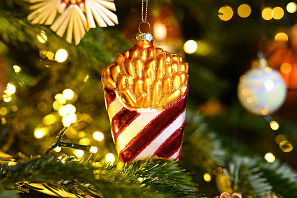 Weihnachtsschmuck in Form einer Tüte Pommes hängt an einem Weihnachtsbaum