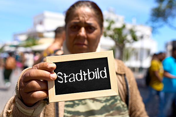 Fotomontage, eine Frau hält ein Schild mit der Aufschrift: Stadtbild. Symbolfoto Stadtbild Debatte in Deutschland