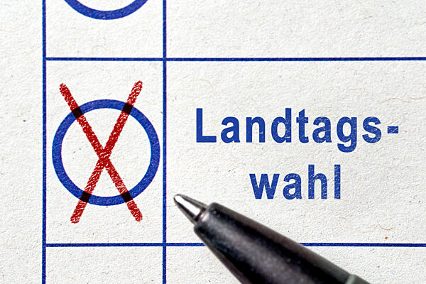 Fotomontage, Nahaufnahme eines Stimmzettels mit gesetztem Kreuz neben dem Begriff Landtagswahl. Symbolbild für demokratische Beteiligung, Stimmabgabe und politische Entscheidung auf Landesebene.