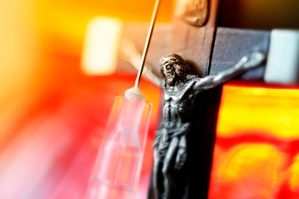 Kreuz an einem Grablicht und Spritze, Symbolfoto Sterbehilfe