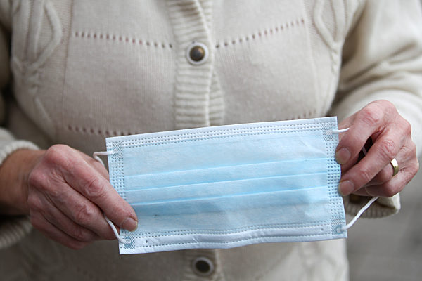 Themenbild - Rentnerin, Seniorin schuetzt sich mit einer Einwegmaske vor dem Coronavirus