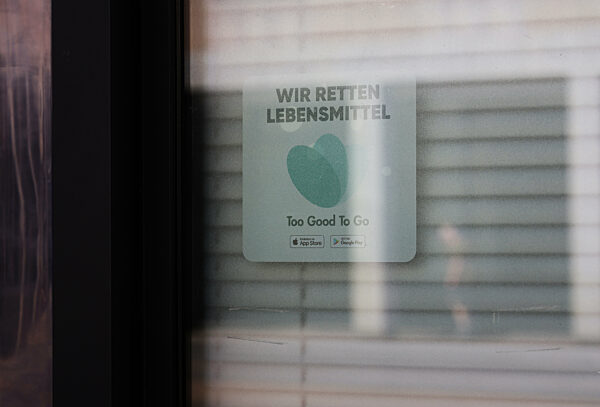 30.05.2023, 
Deutschland, Hessen,
Lebensmittelverschwendung,
Aufkleber hinter einem Fenster mit der Aufschrift Too good to go - wir retten Lebensmittel, App