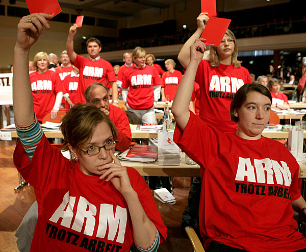 Delegierte mit T-Shirts, die den Aufdruck "Arm trotz Arbeit" tragen...