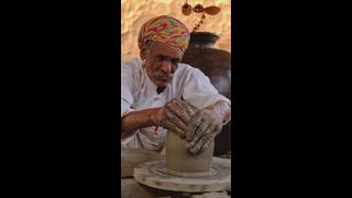 Erfahrener professioneller Töpfer, der die Töpferscheibe wirft und traditionelle Keramikgefäße und Tonwaren formt: Topf, Krug in der Töpferwerkstatt. Handarbeit aus Shilpagram, Udaipur, Rajasthan, Indien