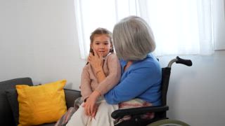 Drei Generationen von Frauen verbringen viel Zeit miteinander. Mit einem kleinen Mädchen, das im Rollstuhl auf dem Schoß ihrer Großmutter sitzt, während ihre Mutter von der Couch aus zuschaut. Spielt gerne ein Klatschspiel