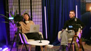 Ersteller von Inhalten, die einen Video Podcast oder ein Interview in einem professionellen Studio aufnehmen, wobei die Frau leidenschaftlich ins Mikrofon spricht, während der Mann während einer Live Übertragung aufmerksam zuhört