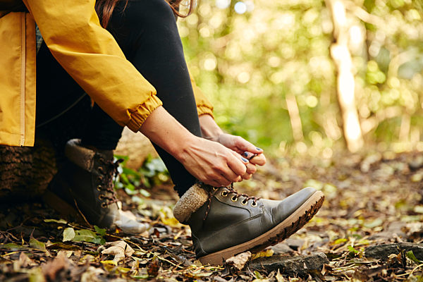 Solo Autumn Walk,United Kingdom,Close up of woman sitting on log tying shoe lace on woodland path