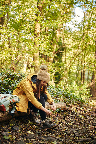Solo Autumn Walk,United Kingdom,Woman sitting on log in woodland tying shoe lace