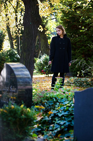 Frau trauert auf einem Friedhof