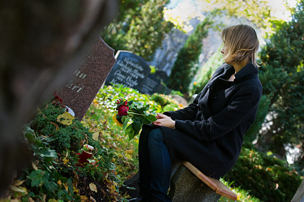 Frau trauert auf einem Friedhof