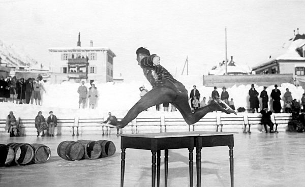 Mann in Schlittschuhen springt Ã_ber einen Tisch, ca...