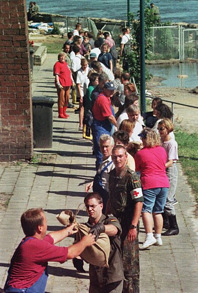 Hochwasser - Menschenkette mit Sandsäcken