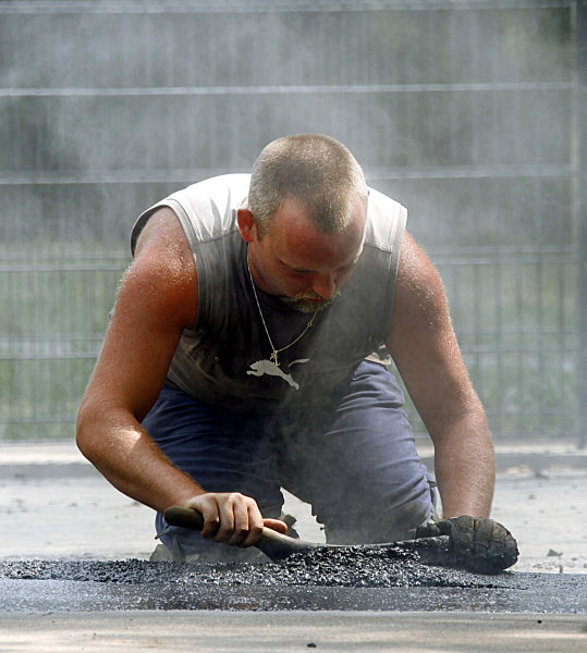 Ein Straßenbauarbeiter verteilt am Dienstag (25.07...