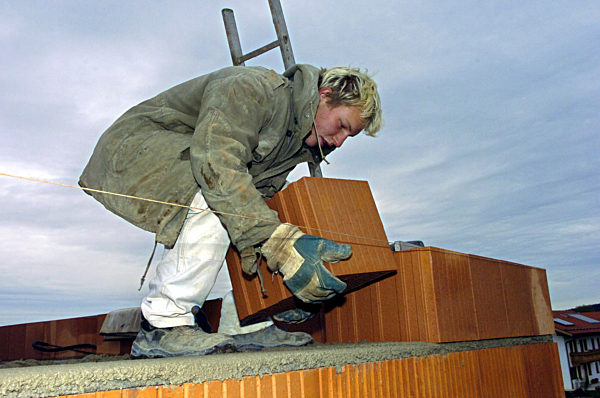 Symbolbild Bau: Ein Maurer arbeitet in warmer Kleidung bei schlechtem Wetter...