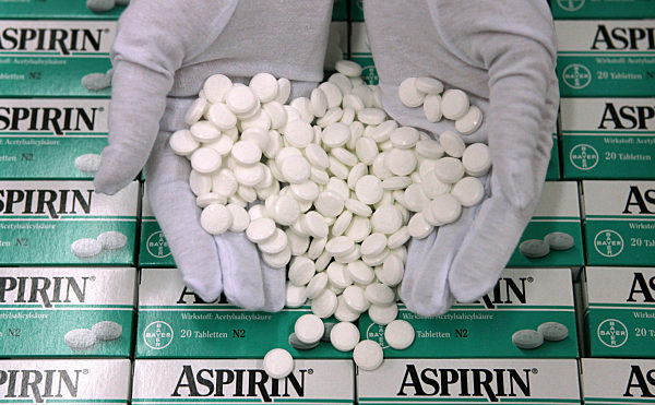 Zwei Hände in weißen Handschuhen zeigen Aspirin-Tabletten in der Bayer...