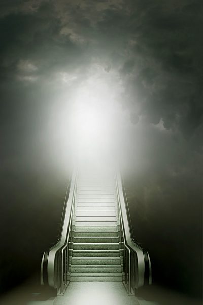 Stairs on escalator leading to glowing light in overcast sky