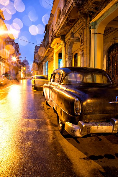 Low light view along a street towards The Capitolio with street lights reflecting in the wet tarmac and wet car bodywork after rain, Havana Centro, Havana, Cuba, West Indies, Central America