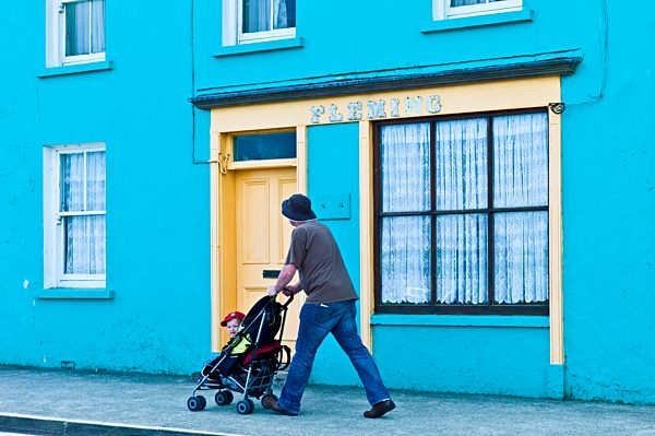 Man wheels child in stroller along the street in Courtmacsherry, County Cork, Ireland