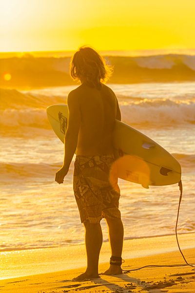 Surfer at sunset on this popular surf beach near Mal Pais on the Nicoya Peninsula; Playa Santa Teresa, Puntarenas, Costa Rica