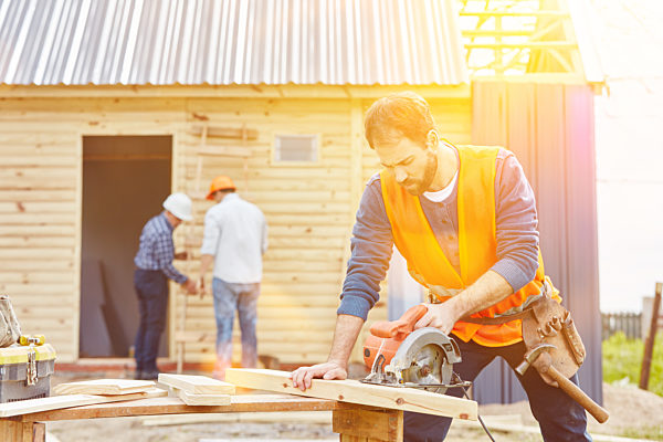 Handwerker mit Handkreissäge beim Hausbau