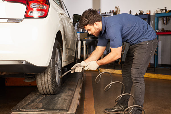KFZ Mechaniker beim Reifenwechseln vom Auto