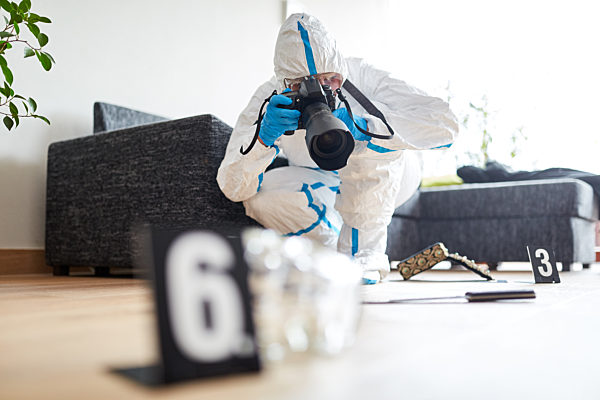 Kriminaltechniker mit Kamera fotografiert Tatort