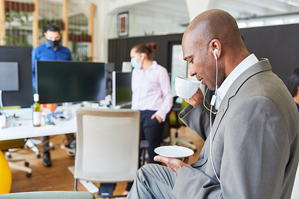 Business Mann mit In-Ear Kopfhörer und Kaffeetasse