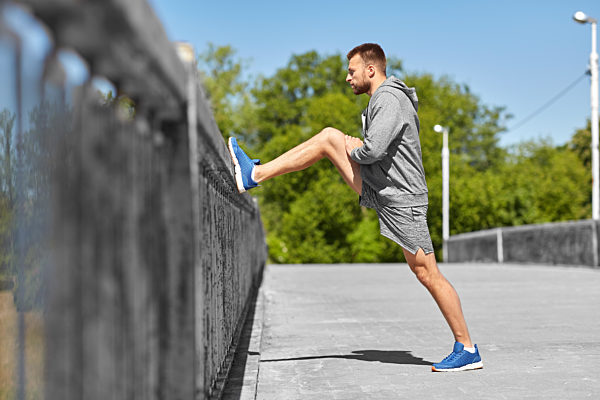 man stretching leg on bridge