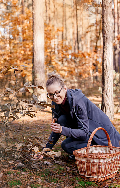 Girl with glasses in the autumn forest. Woman with a a basket walks in the woods. Autumn walk.